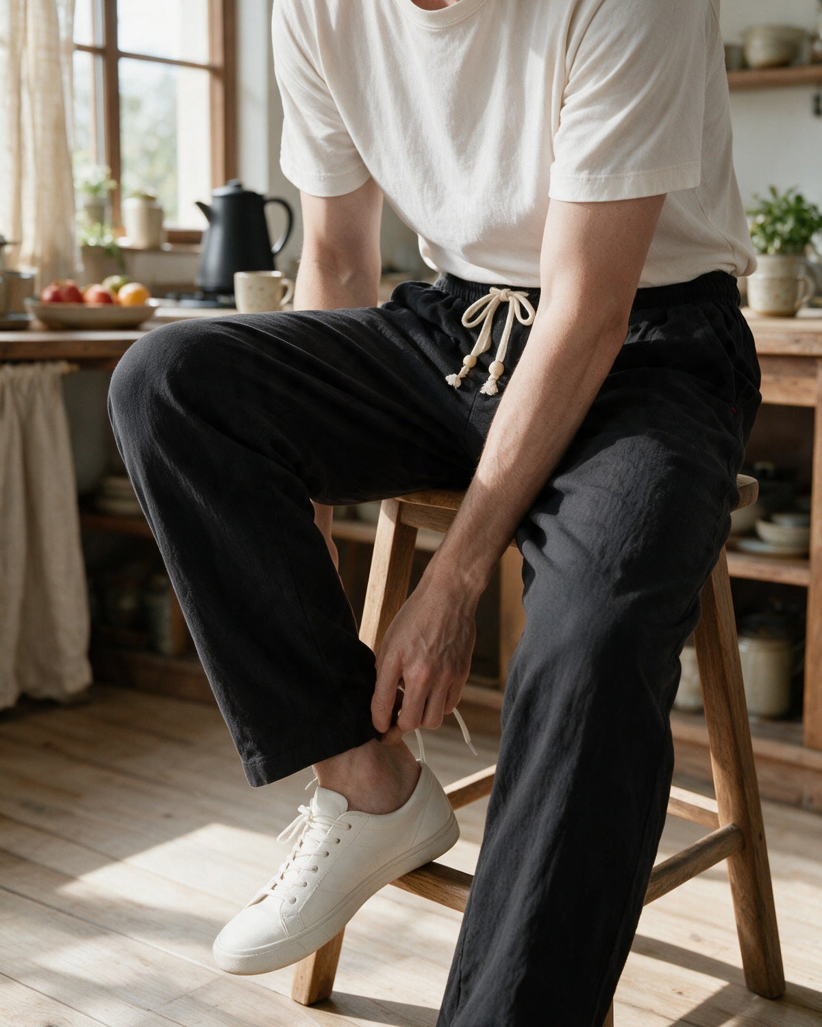 Whitby drawstring trousers in Black, putting on trainers in the kitchen